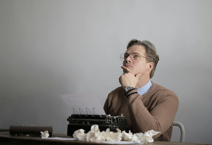 Hombre escribiendo en una máquina de escribir y pensativo