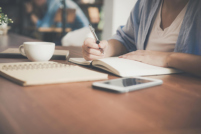 Una mujer escribiendo. Un cuaderno y una tableta