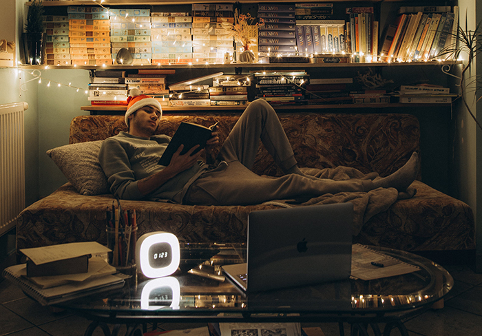 Un chico leyendo acostado en una sofá en tiempos de Navidad