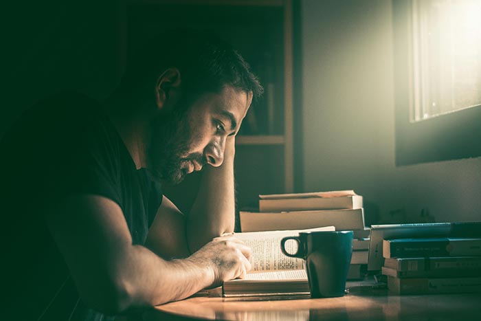 Un joven leyendo junto a una taza de café